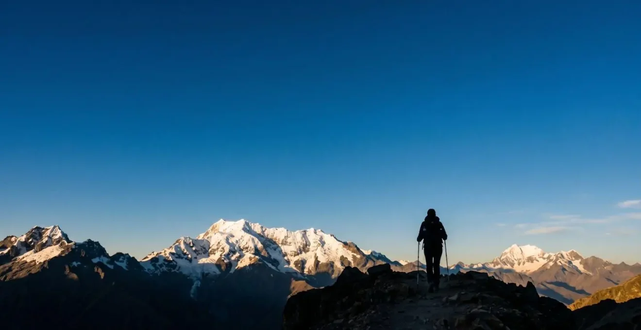 Randonneur équipé face à un sommet enneigé des Andes à plus de 4000 mètres d'altitude sous un ciel bleu profond